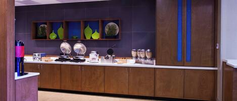 A modern kitchen with wooden cabinets, a countertop with various appliances, and decorative wall art.