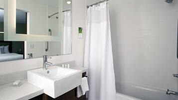 A modern bathroom with a white sink, mirror, and shower curtain.