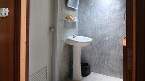 Un baño pequeño con un lavamanos blanco, un espejo y una repisa con un objeto amarillo.