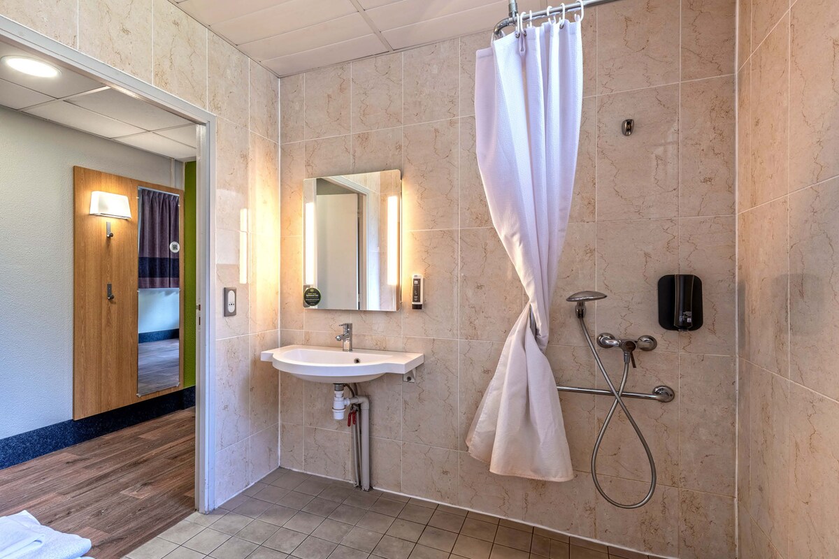 A modern bathroom with a sink, mirror, shower, and towel rack.