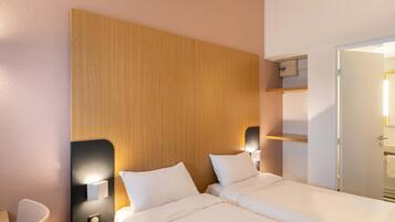 A hotel room with a wooden headboard, two beds, a desk, and a mirror.