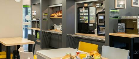 Un moderno comedor con asientos, refrigerador y cafetera.