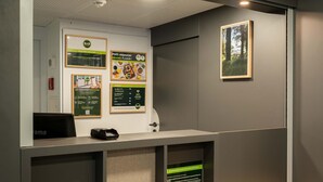 Una recepción con un cartel de B&B, un cuadro con árboles y carteles informativos en la pared.