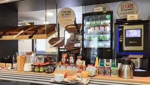 A breakfast bar with various food items, a coffee machine, and a refrigerator with dairy products. - B&B HOTEL Chalon-sur-Saône Sud (Saint-Remy)