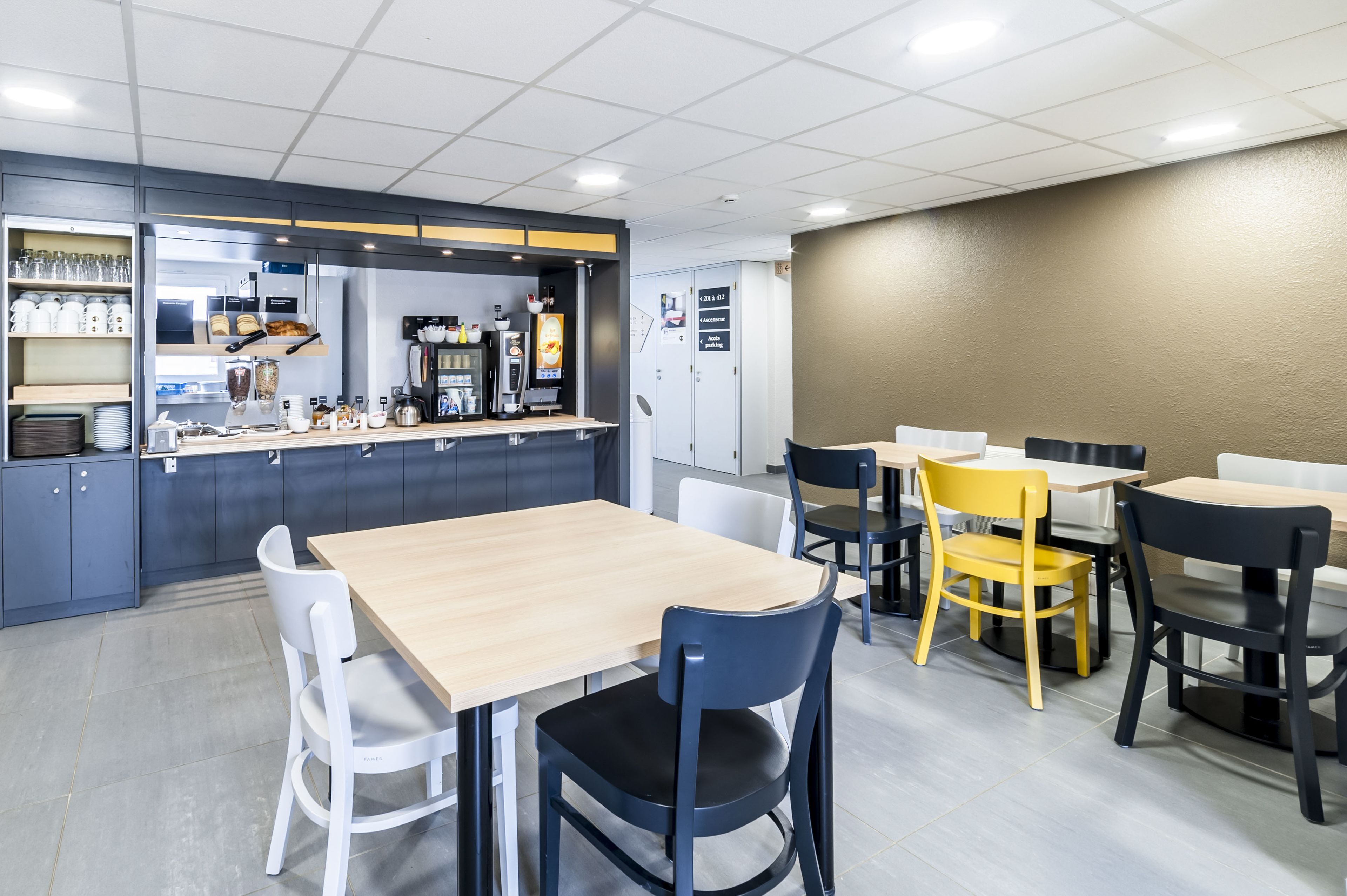 A modern cafe with a counter, seating area, and a wall-mounted menu board.