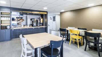 A modern cafe with a counter, seating area, and a wall-mounted menu board.