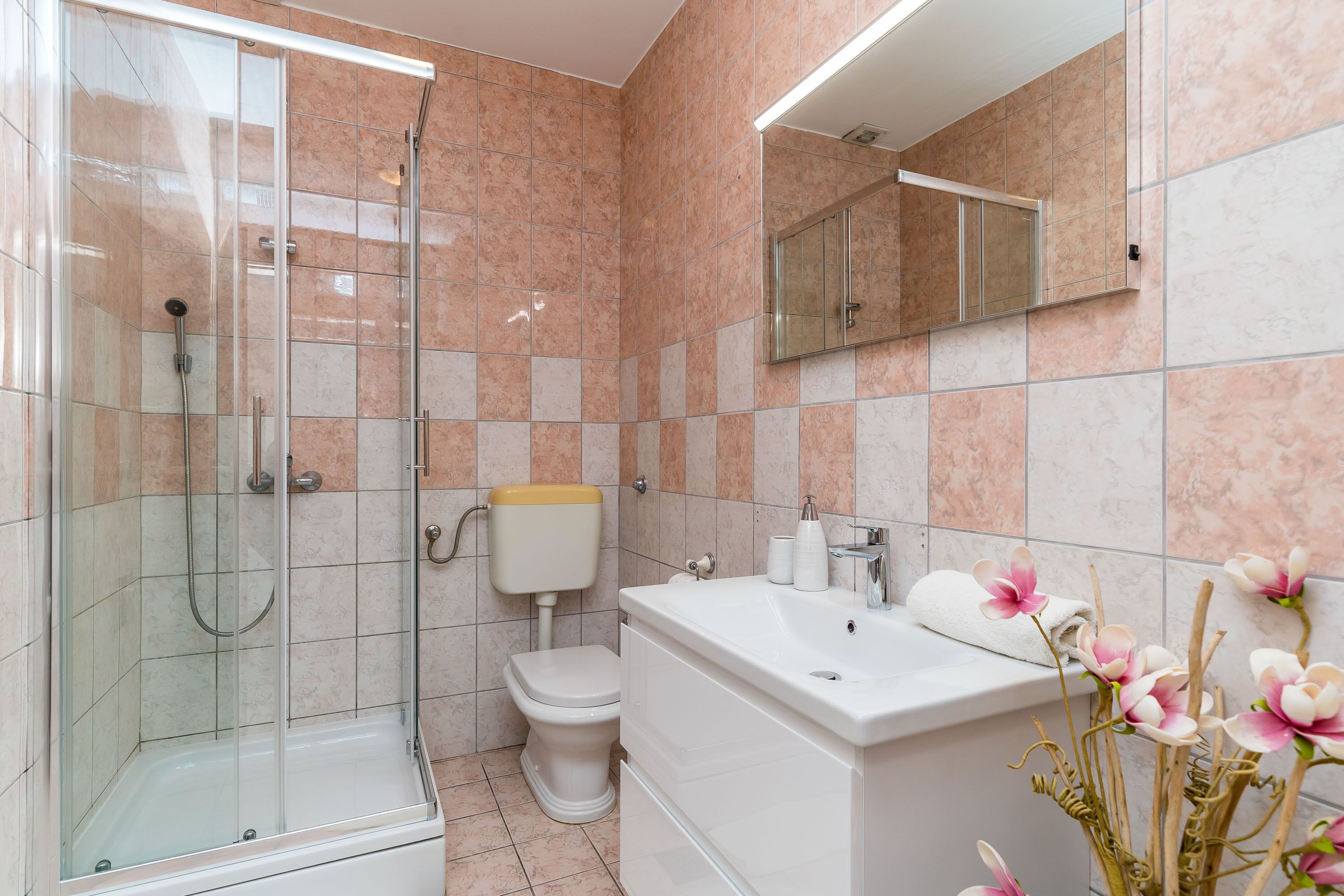 Un baño con ducha de vidrio, inodoro y lavabo con espejo.