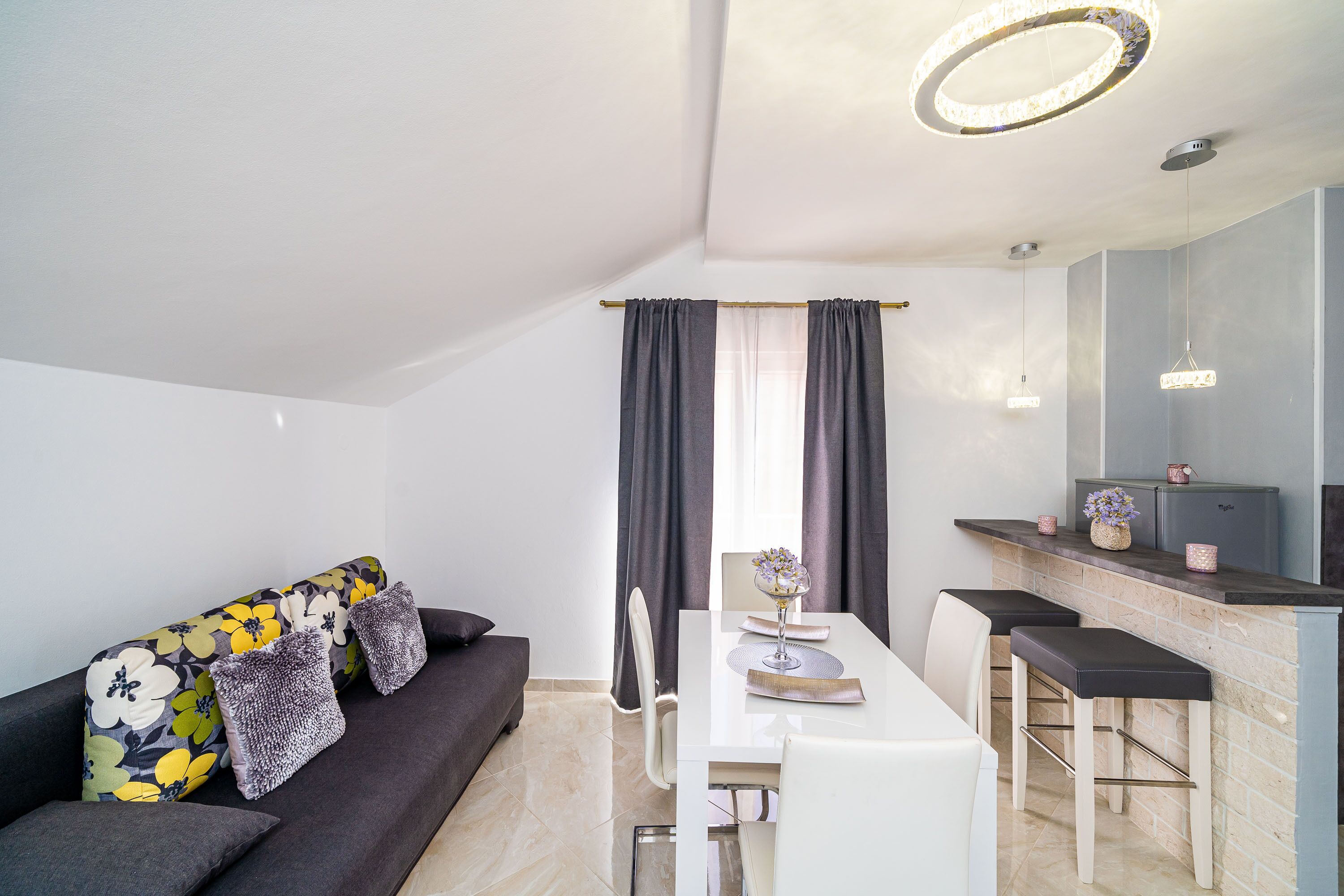 Una sala de estar moderna con sofá, mesa de comedor y zona de bar.