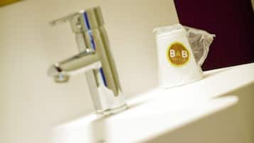 A bathroom sink with a towel rack, a soap dispenser, and a plastic bag with a hotel logo.