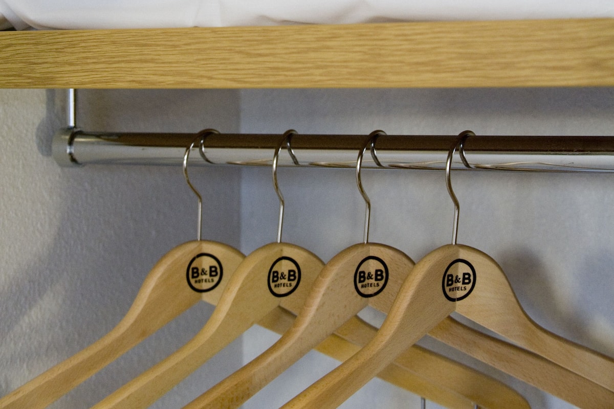 A neatly folded white towel on a shelf with wooden hangers below.