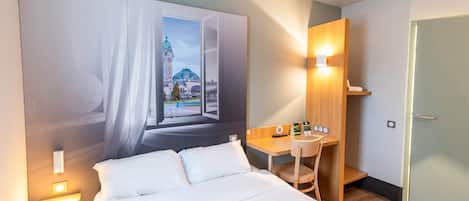 Una habitación de hotel con una cama grande, un escritorio y un televisor montado en la pared.