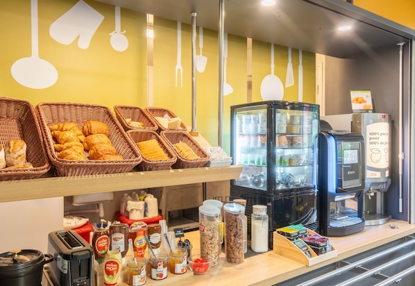 A breakfast buffet with baskets of pastries, a coffee machine, and various condiments.