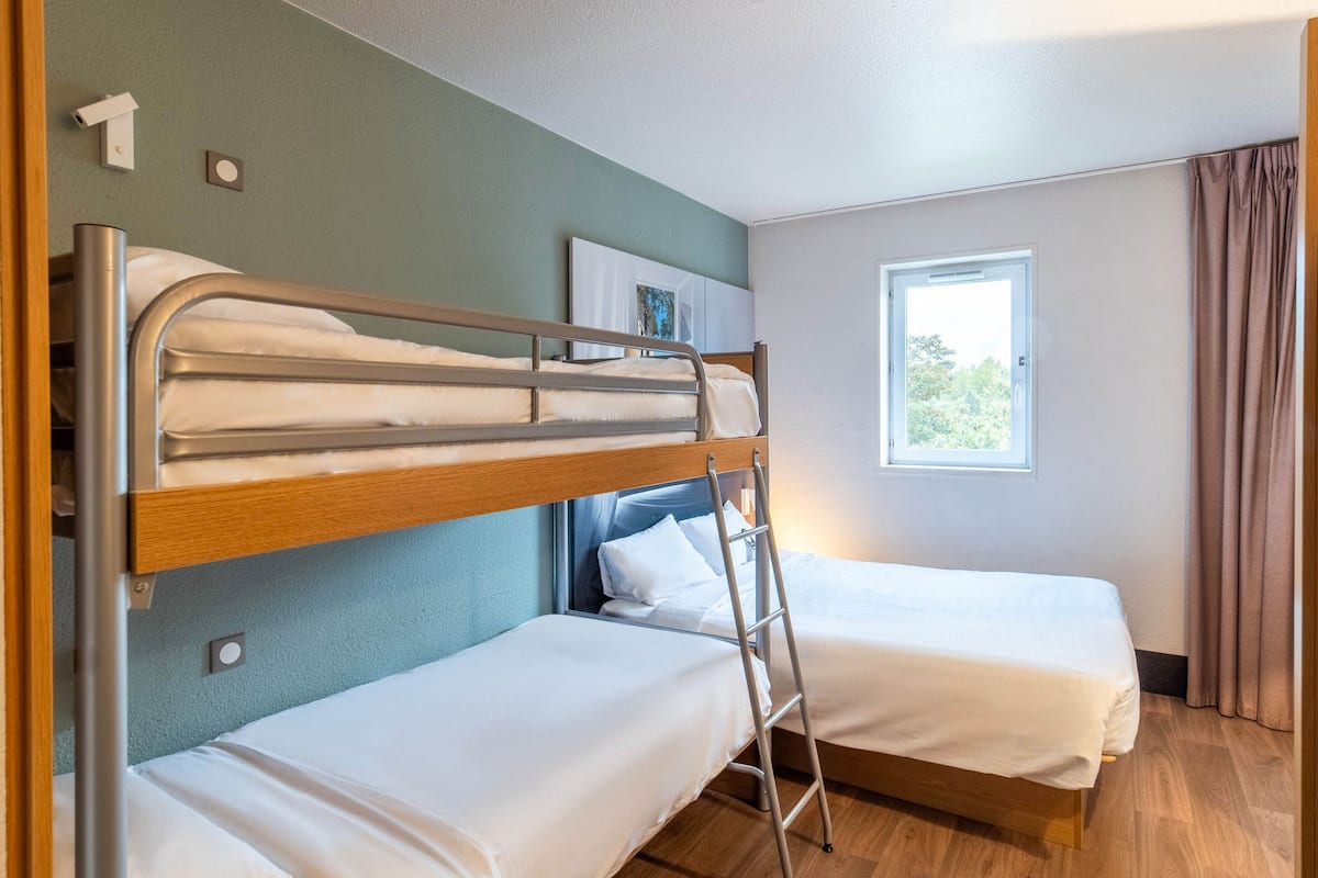 A room with bunk beds, a ladder, a window, and a door.