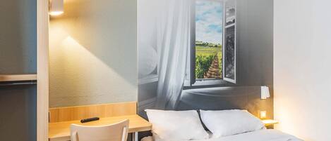 Habitación de hotel con cama, escritorio, silla y televisor de pared mostrando vista a viñedos.