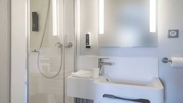A modern bathroom with a glass shower enclosure, a white sink, and a mirror with integrated lighting.