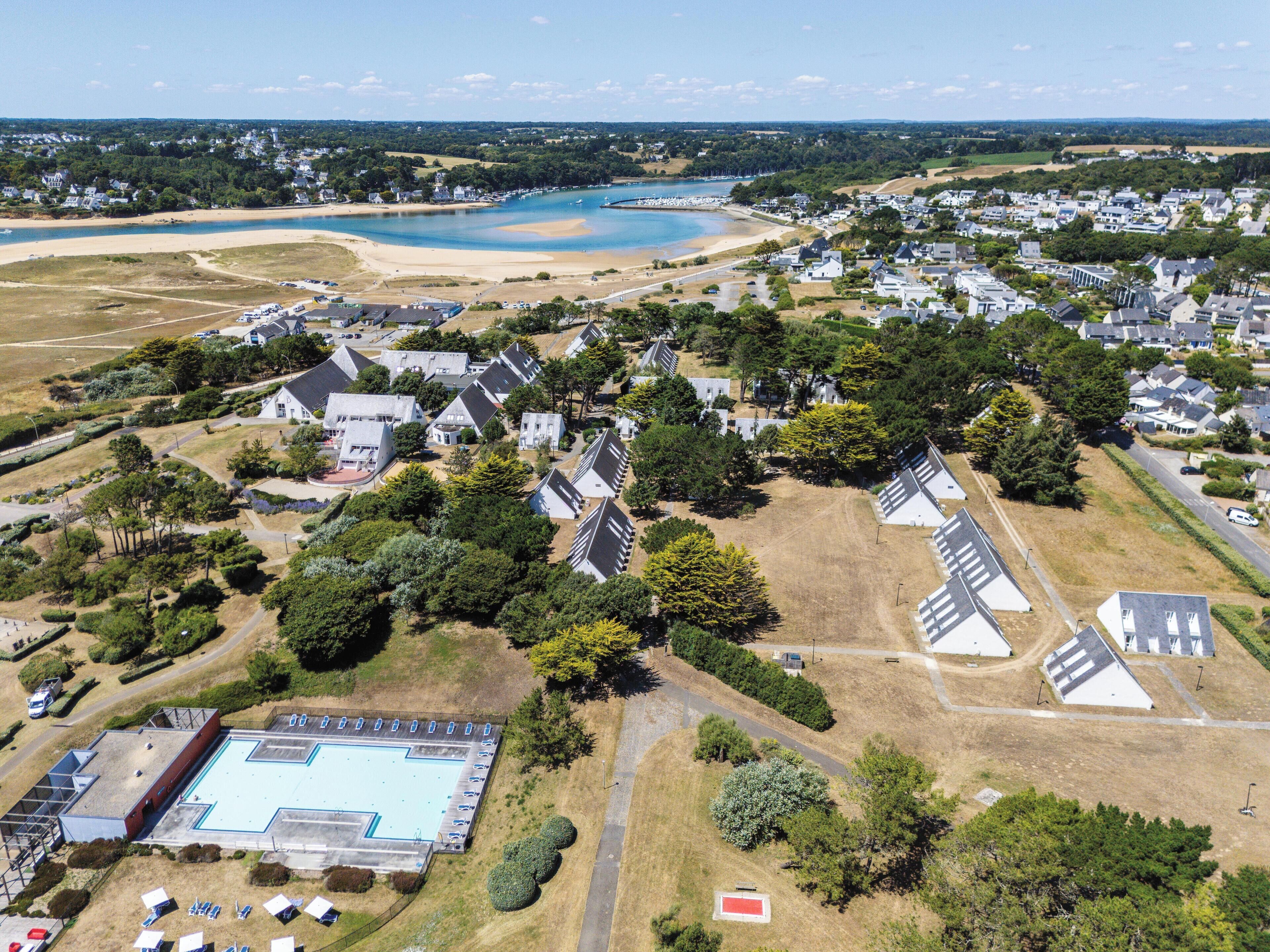 Vue aérienne d’un quartier résidentiel avec des maisons, une plage et une piscine.