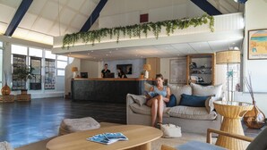 A spacious lobby with a reception desk, seating area, and large windows. - Belambra Clubs Guidel - Les Portes De L'Océan (Guidel)