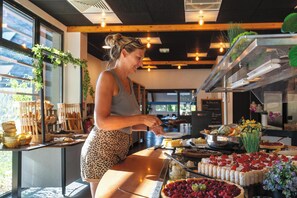 Una mujer sirviendo comida en un bufé con diversos platos y una barra de ensaladas.