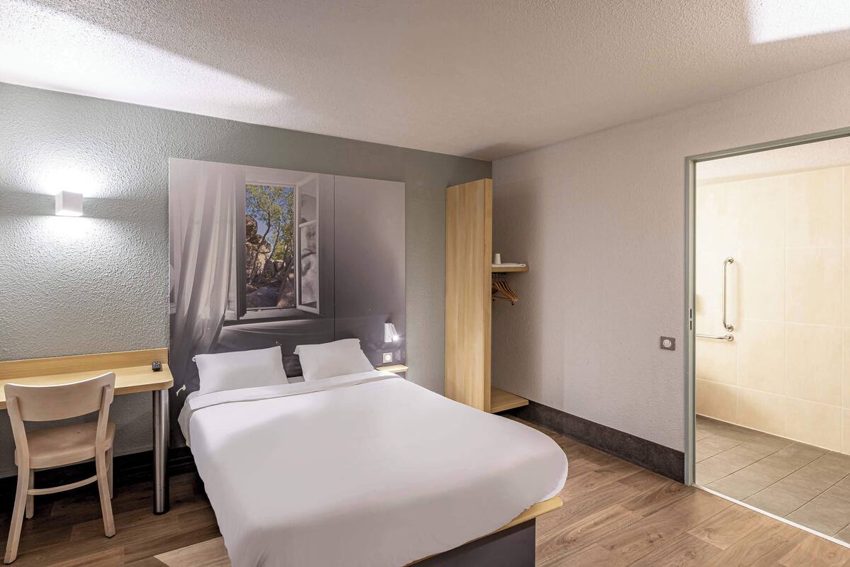 Quarto de hotel moderno com cama, escrivaninha e guarda-roupa.
