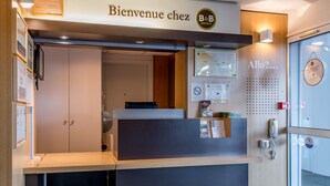 Un mostrador de recepción con un cartel que dice "Bienvenue chez B&B Hotels" y un teléfono instalado en la pared.