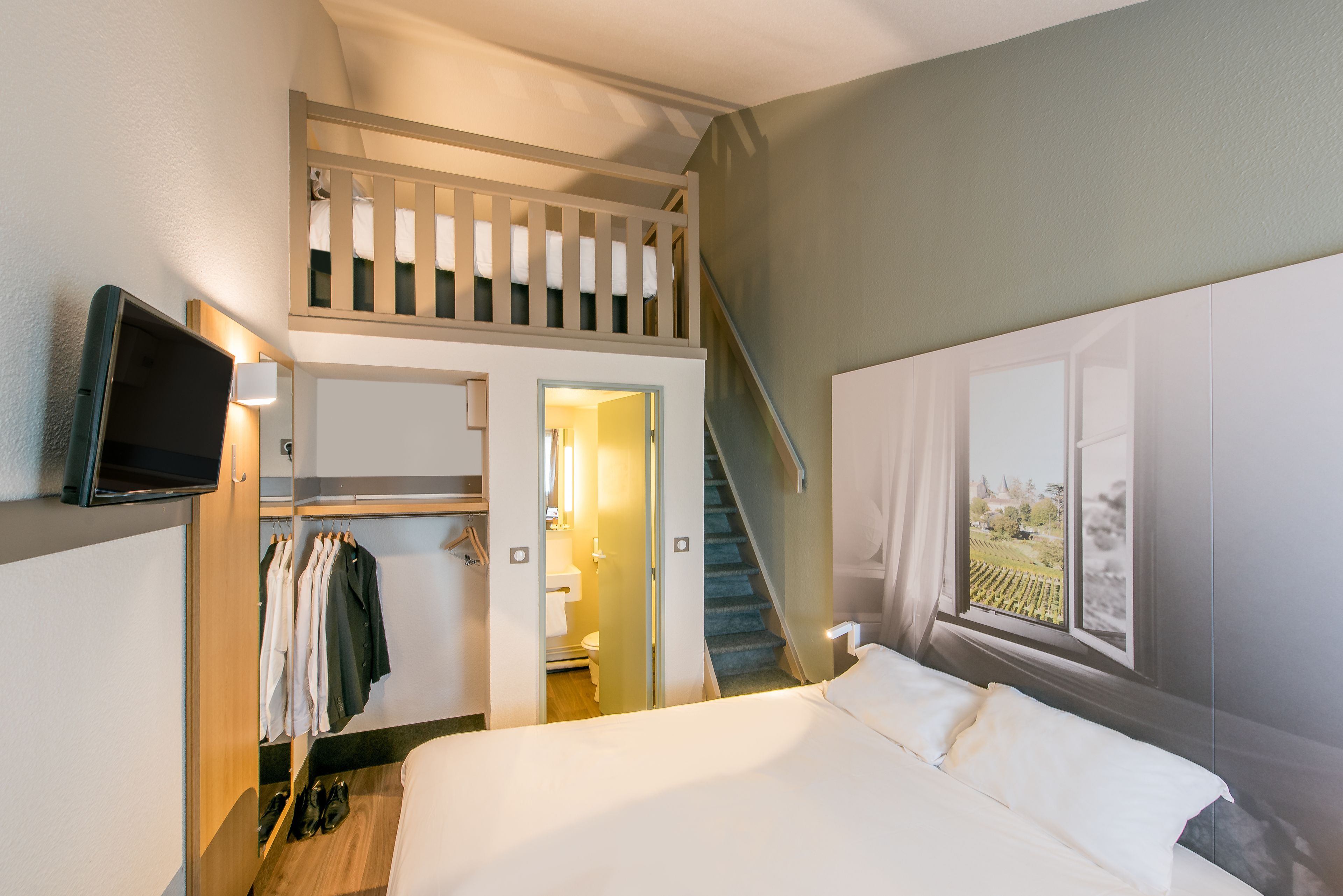 A bedroom with a bunk bed, a TV, a closet, and a window with a view.