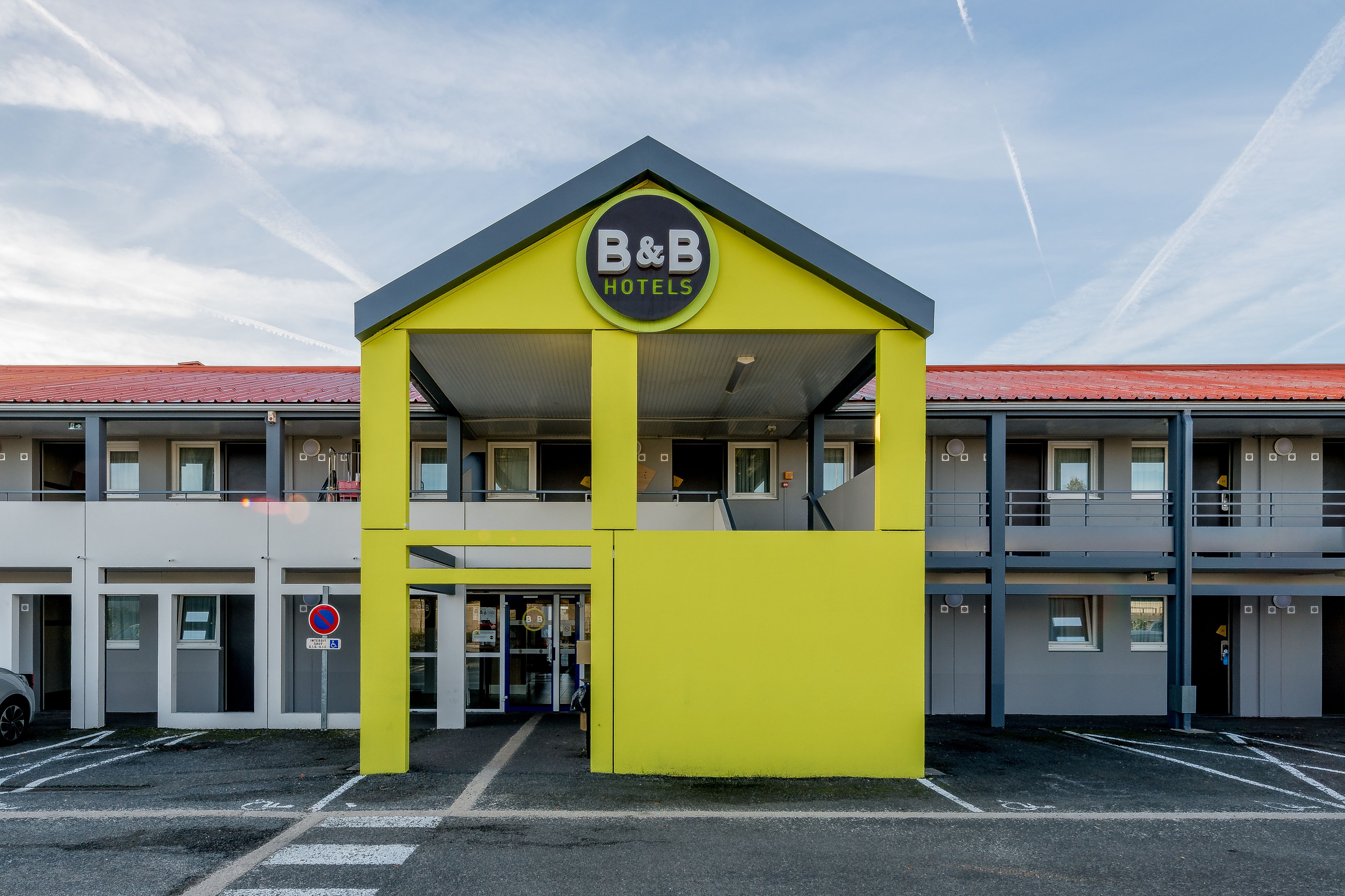 A B&B hotel with a yellow facade, a covered entrance, and a red roof.