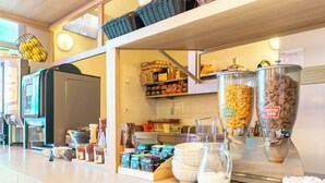 A breakfast bar with various food items, including cereal and milk, and a coffee machine. - B&B Hôtel Nantes Centre (Nantes)