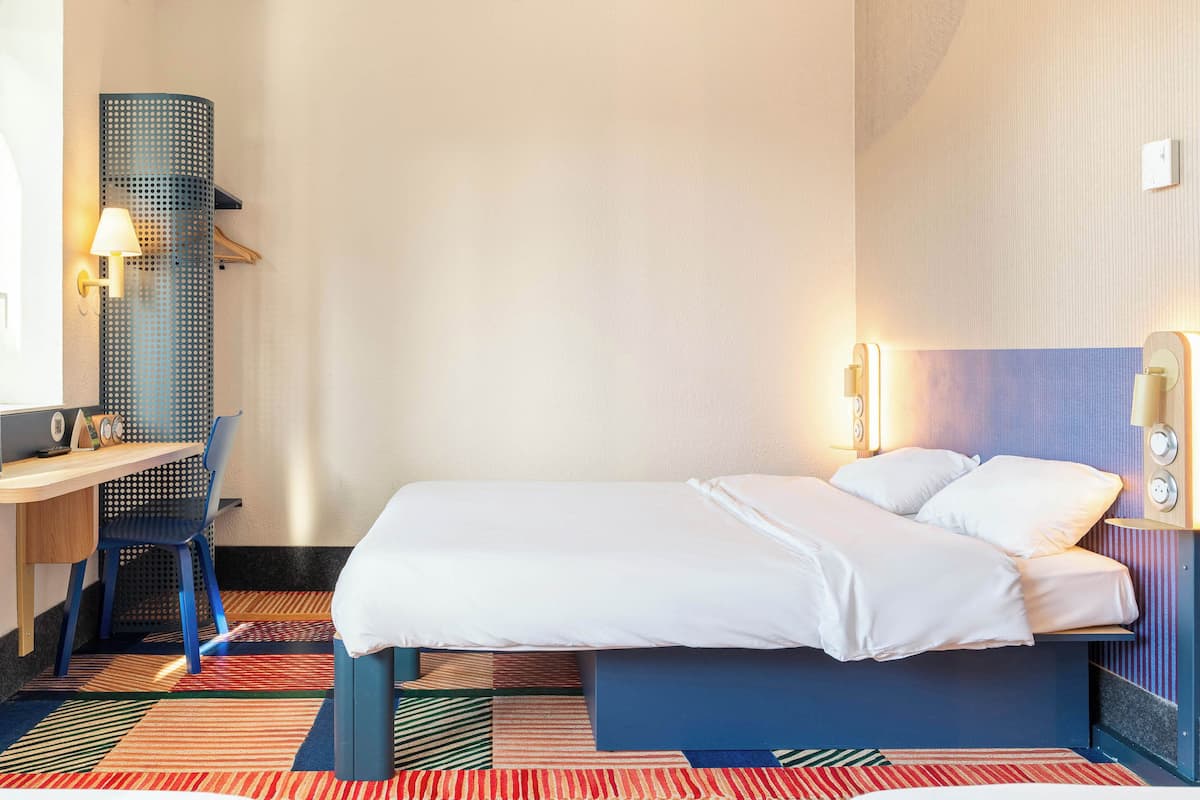 Una habitación de hotel con una cama, un escritorio y una silla.
