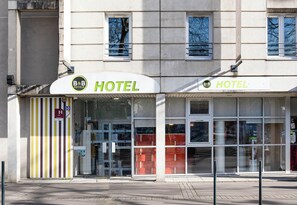 A hotel with a striped facade, large windows, and a clear view of the interior. - B&B Hôtel Nantes Centre (Nantes)