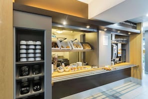 Zona de desayuno tipo buffet con diversas opciones de comida y una máquina de café.