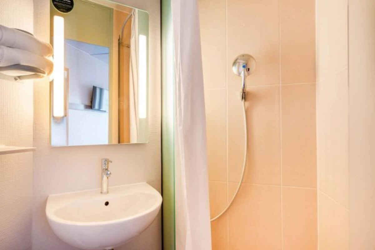 Een badkamer met een wit wastafelmeubel, een spiegel en een douche met een handdouche.