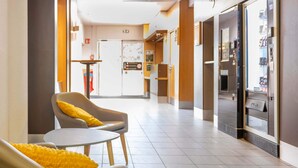 Un hall d’hôtel avec des sièges, un distributeur automatique et une porte au fond.