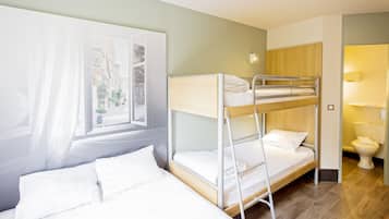 A hotel room with a bunk bed, a single bed, a window with curtains, a framed picture, and a toilet.