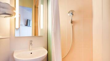 Une salle de bain avec un lavabo blanc, un miroir et une douche.