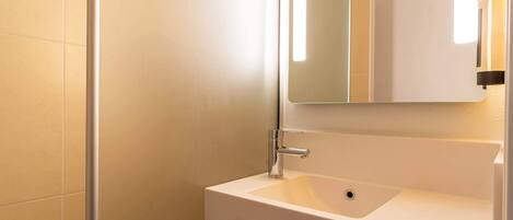 Un baño con un lavabo blanco, un espejo y una toalla colgada en la pared.