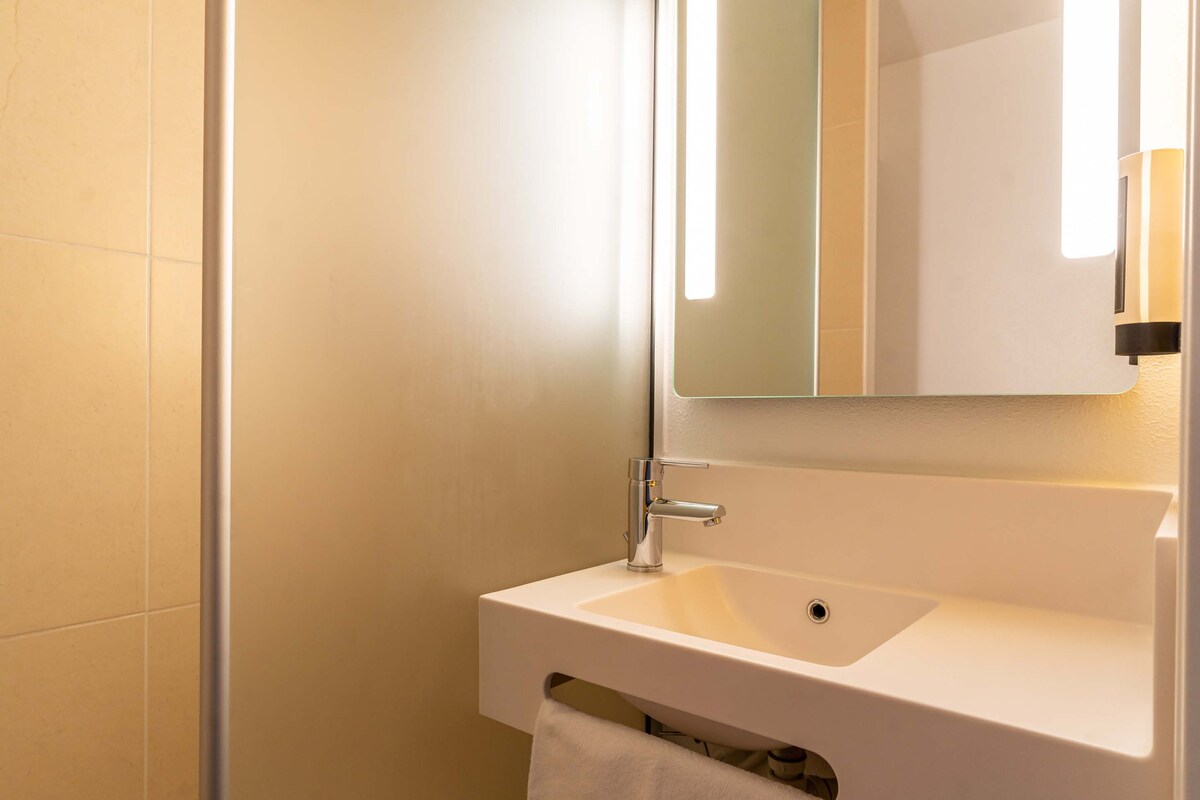 Une salle de bain avec un lavabo blanc, un miroir et une serviette accrochée au mur.