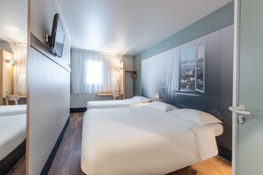 Habitación de hotel con dos camas, un televisor montado en la pared, una ventana con vistas a un paisaje montañoso y suelo de madera.