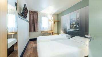A hotel room with two beds, a desk, a chair, and a window with a view.