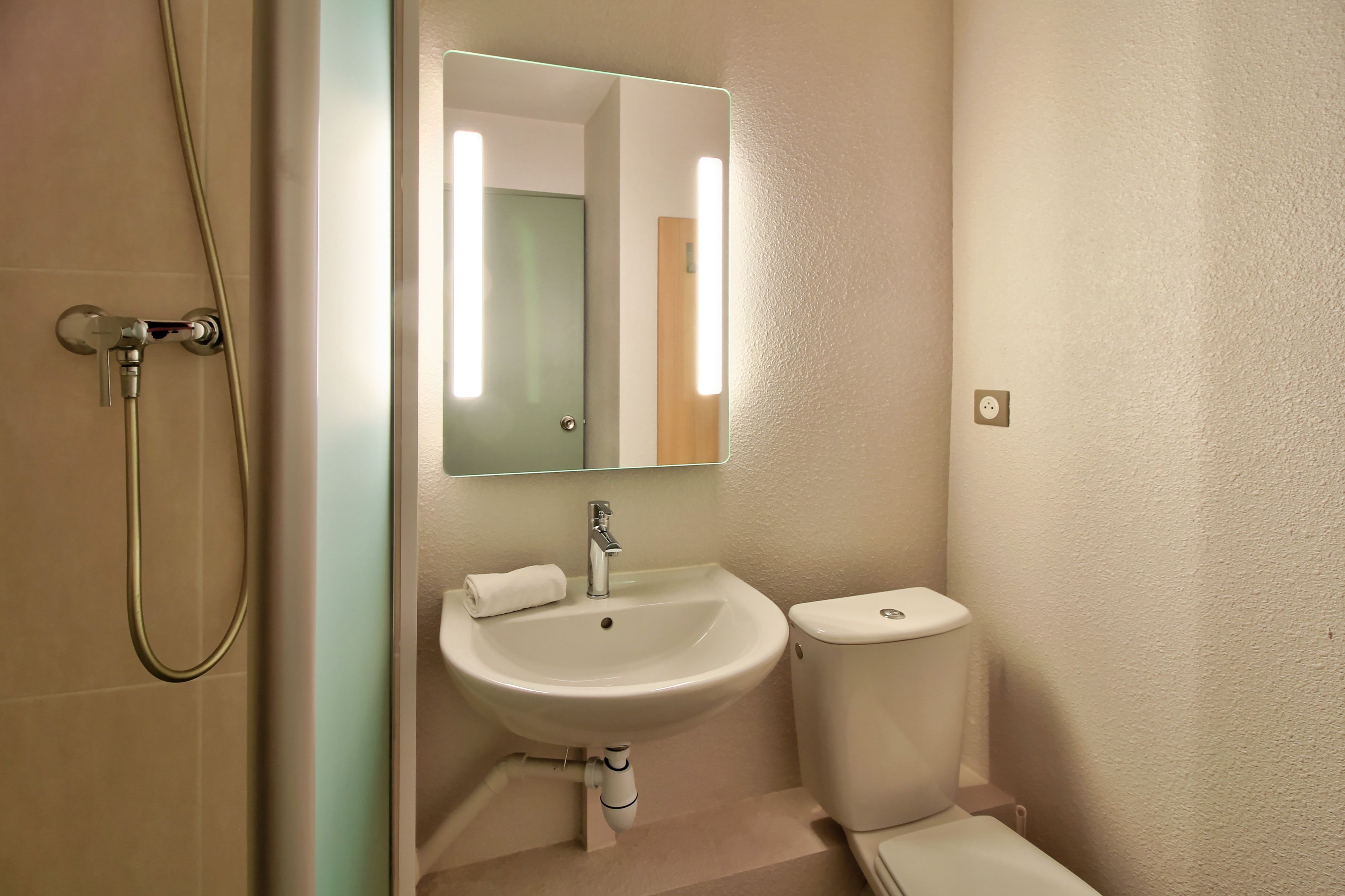 A bathroom with a sink, mirror, toilet, and shower.