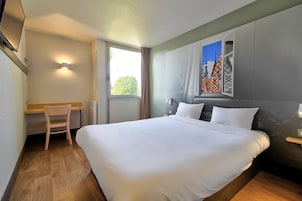 Habitación de hotel con una cama grande, un escritorio y una ventana con cortinas.