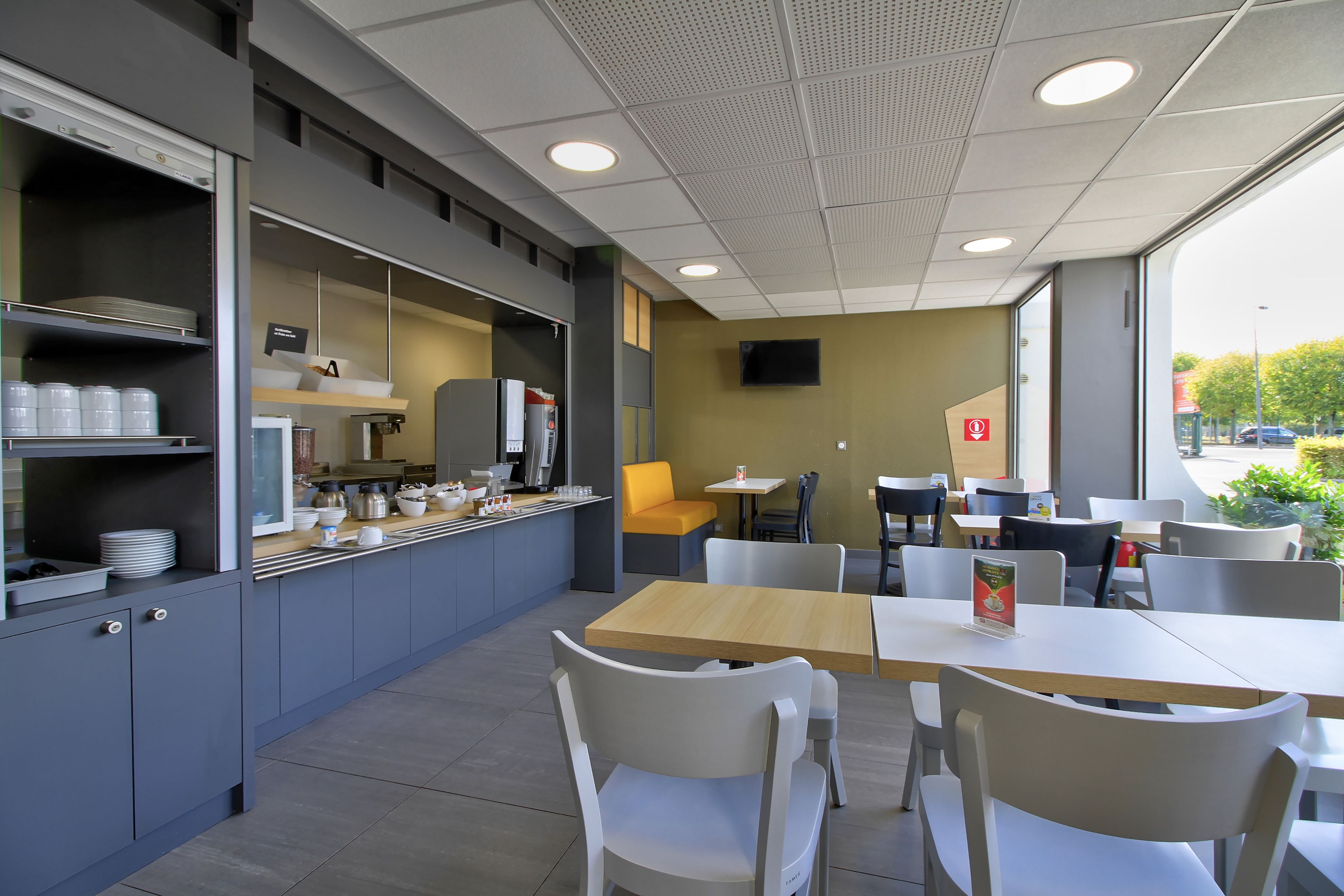 A modern cafe with a counter, seating area, and large windows.