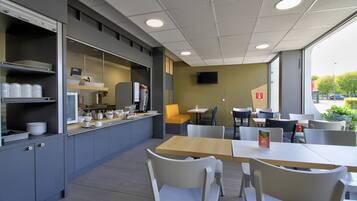 A modern cafe with a counter, seating area, and large windows.
