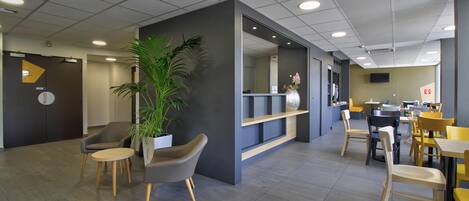 A modern waiting area with seating, a plant, and a reception desk.