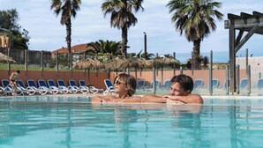 Una piscina con sillas de descanso y palmeras al fondo.
