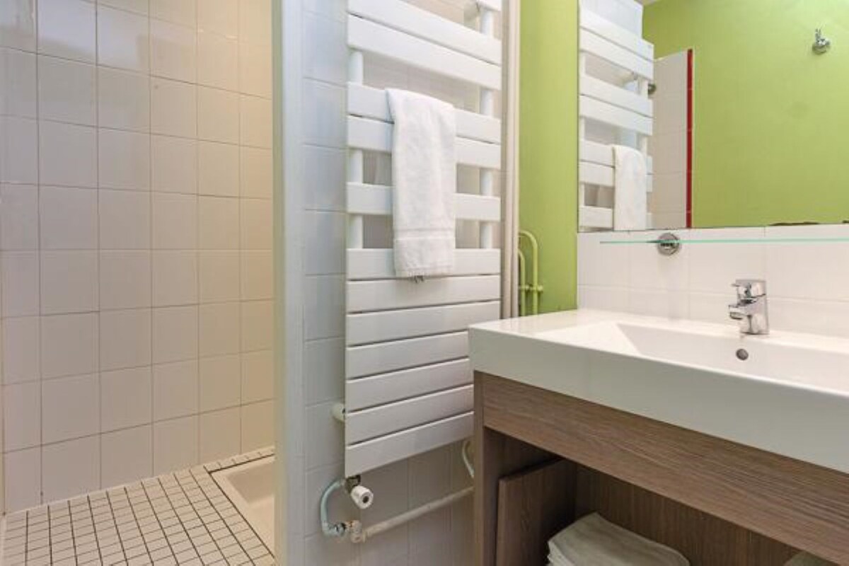 Une salle de bain avec une douche, un lavabo et un miroir.