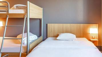 En våningssäng med en stege, en enkelsäng med ett trägavelt och ett nattduksbord med en lampa.