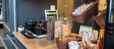 A breakfast bar with various food items, including jars of jam, bread, and baskets.