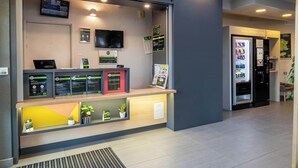 A reception area with a digital screen, a refrigerator, and a small plant display. - B&B HOTEL Brive-la-Gaillarde (Ussac)