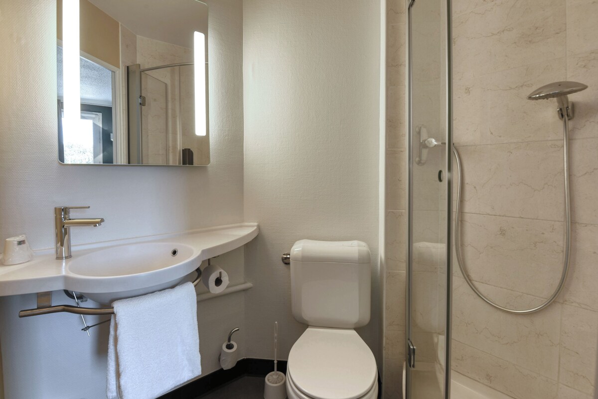 A modern bathroom with a sink, toilet, and shower.