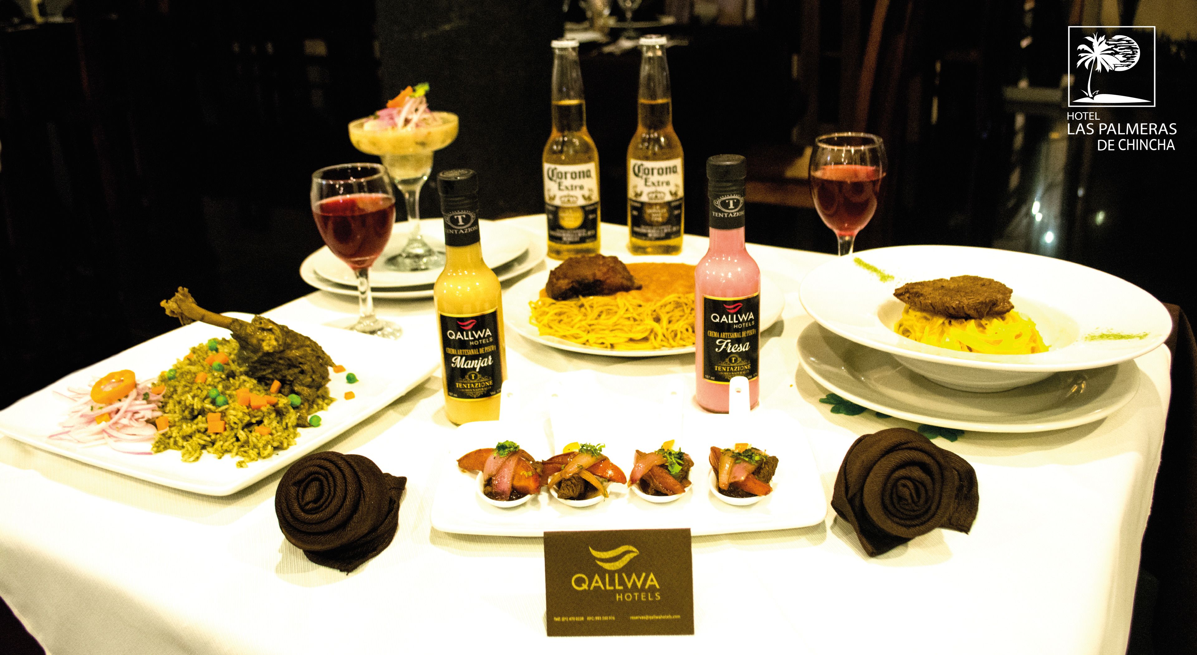 A dining table with various dishes, drinks, and a Qallwa Hotels logo.